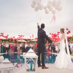 Para młoda wypuszcza balony na weselu w piątek. Goście z czerwonymi balonami tworzą radosną atmosferę.