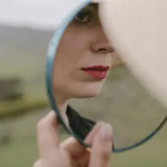 Kobieta z czerwonymi ustami patrzy w lusterko, odkrywając swoją twarz. Zasada lustra w naturze.