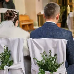 Para młoda siedzi w kościele. Krzesła ozdobione zielonymi gałązkami. Kto nie może być świadkiem na ślubie kościelnym?