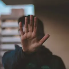 Dłoń zasłania twarz, symbolizując stanowcze "stop" dla obraźliwych słów. Ucz się, jak nie dać się obrażać.