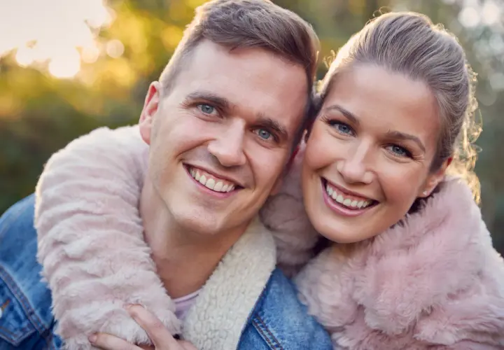 Uśmiechnięta para w jesiennym słońcu. Szukasz pomysłów na randkę z mężem? Spędźcie czas razem na łonie natury!