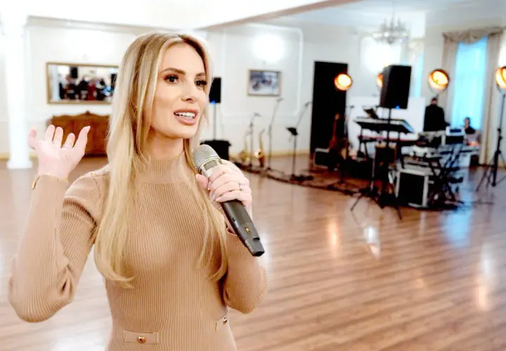 Wokalistka z mikrofonem zapowiada piosenki na ślub. W tle zespół muzyczny i instrumenty.