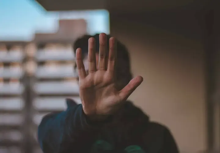 Dłoń zasłania twarz, symbolizując stanowcze "stop" dla obraźliwych słów. Ucz się, jak nie dać się obrażać.