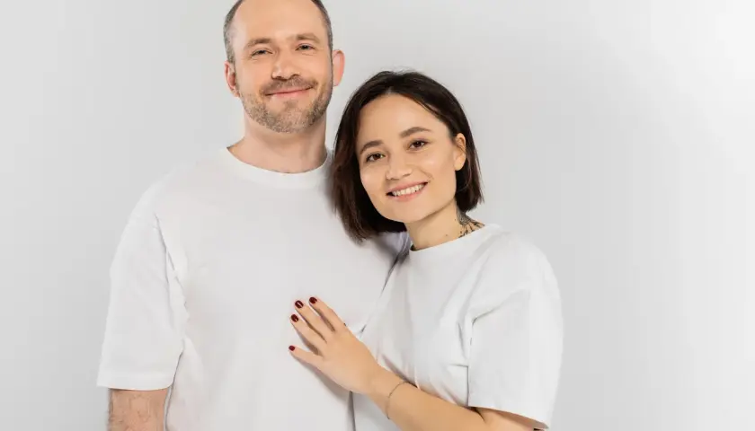 Uśmiechnięta para w białych koszulkach. Idealni kandydaci do rozmowy na randce, szukający wspólnych tematów.