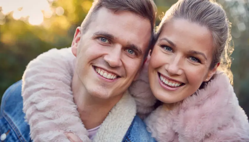 Uśmiechnięta para w jesiennym słońcu. Szukasz pomysłów na randkę z mężem? Spędźcie czas razem na łonie natury!