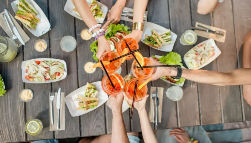 Wspólne toasty z przyjaciółką przy drinkach i przekąskach na drewnianym stole. Idealny sposób na spędzenie czasu.