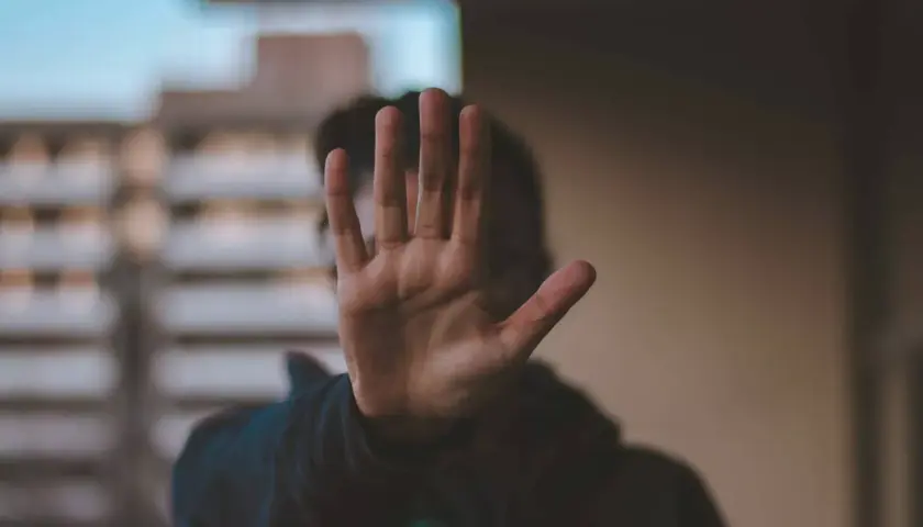 Dłoń zasłania twarz, symbolizując stanowcze "stop" dla obraźliwych słów. Ucz się, jak nie dać się obrażać.