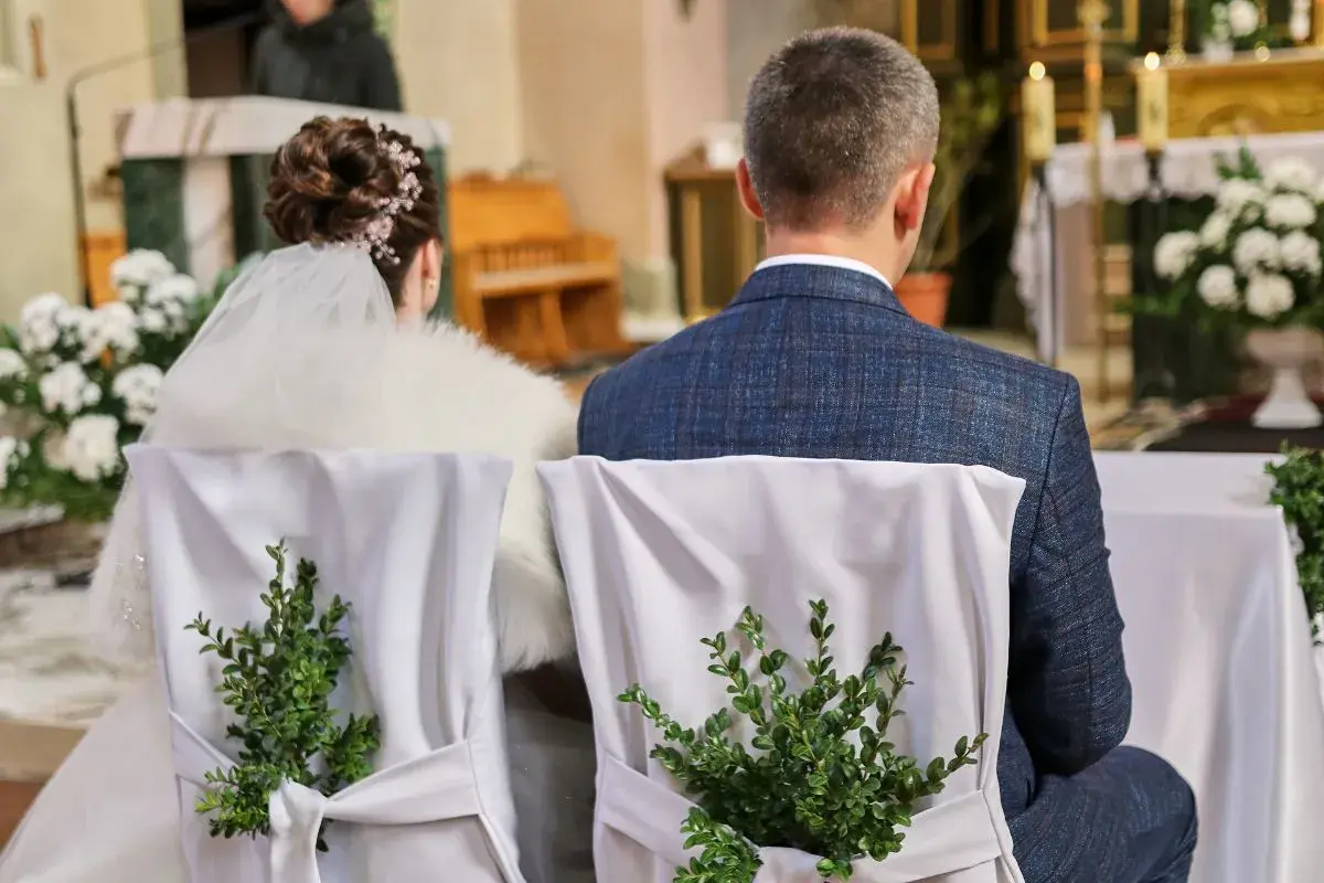Para młoda siedzi w kościele. Krzesła ozdobione zielonymi gałązkami. Kto nie może być świadkiem na ślubie kościelnym?