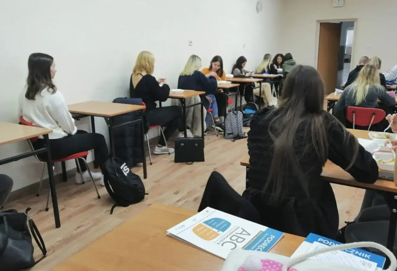 Młodzież uczestniczy w ciekawych zajęciach o emocjach, siedząc przy ławkach w sali lekcyjnej.