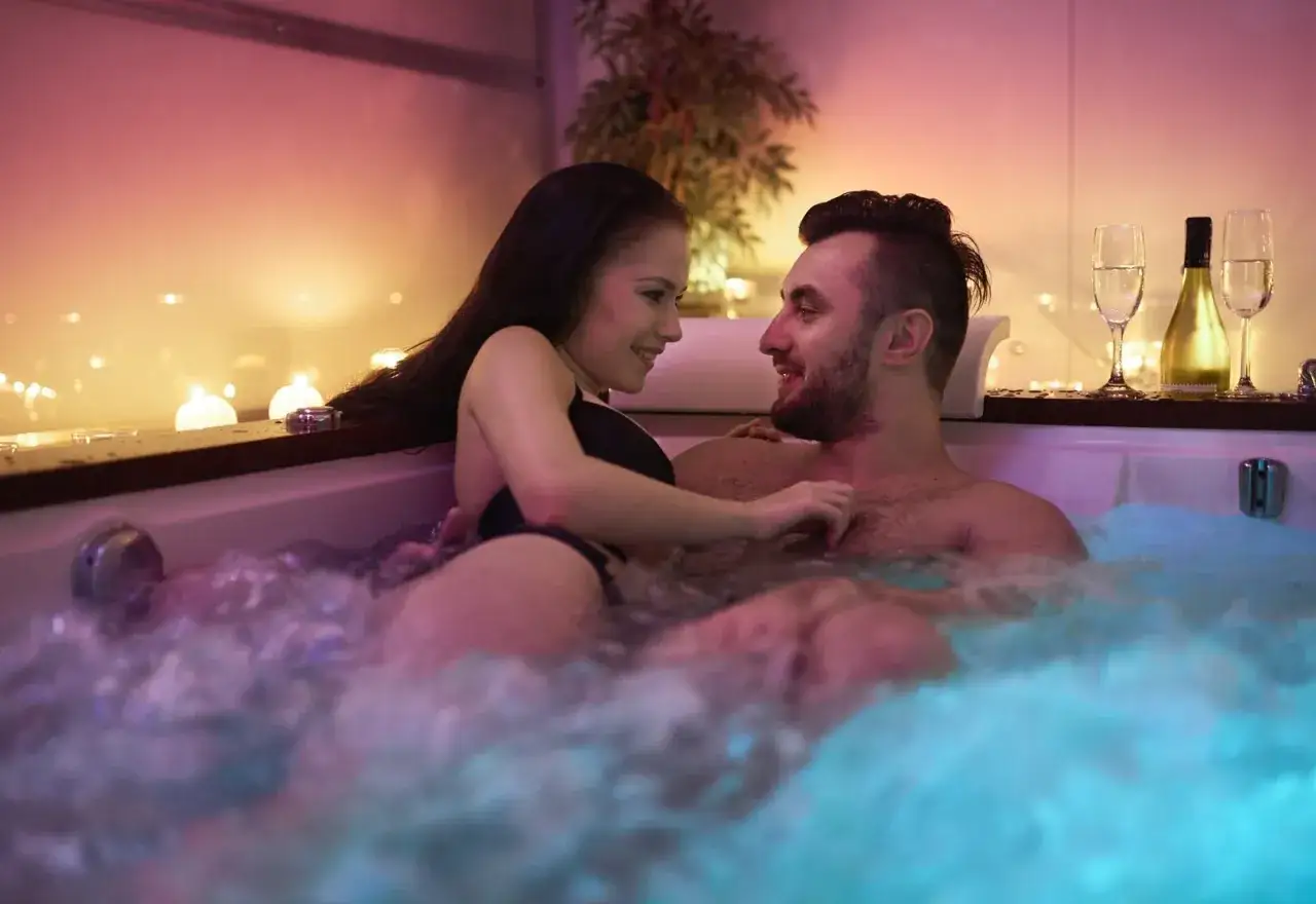 Para romantyczna randka z mężem: para w jacuzzi z szampanem i świecami.