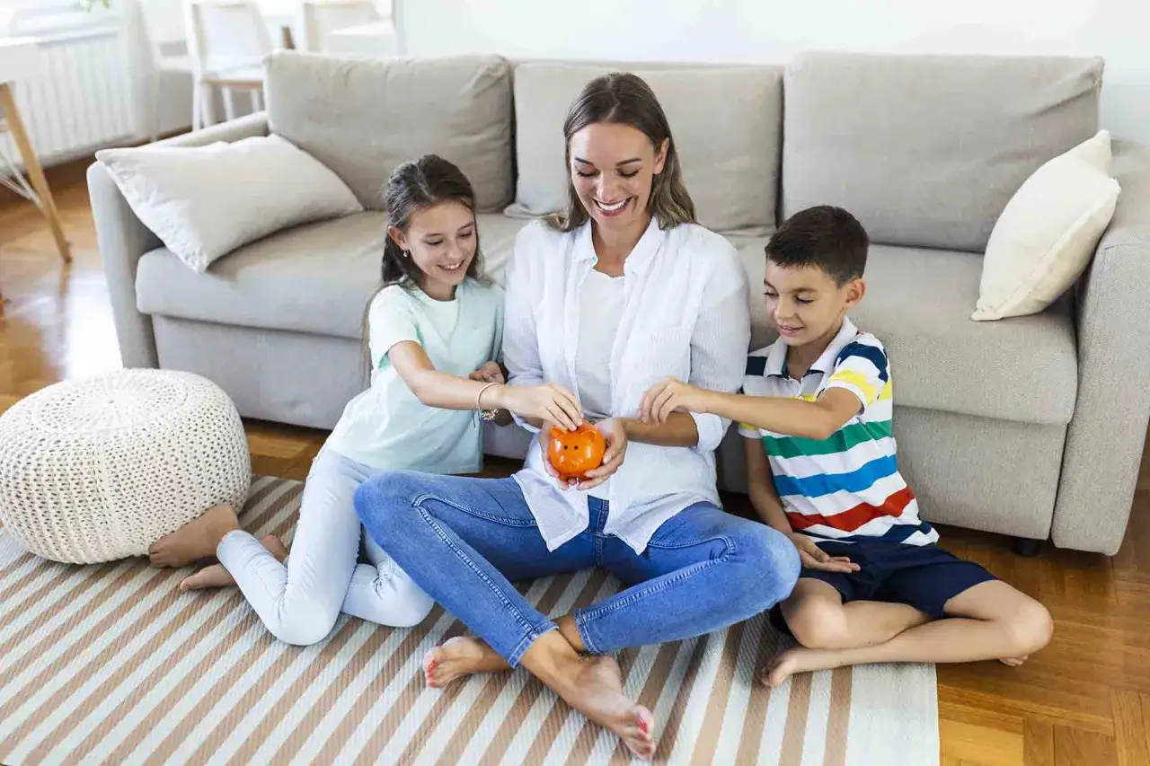Mama z dziećmi wrzuca monety do skarbonki świnki. Uczą się oszczędzać kieszonkowe dla dziecka.