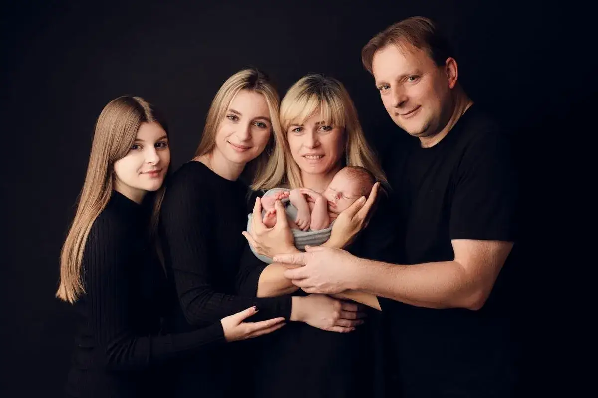 Szczęśliwa mama i syn, otoczeni przez rodzinę, pozują do pamiątkowego zdjęcia.